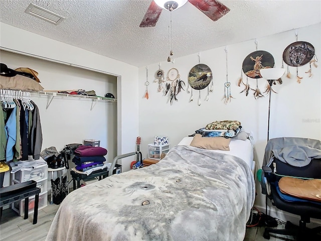 bedroom featuring ceiling fan, light wood-type flooring, and a textured ceiling