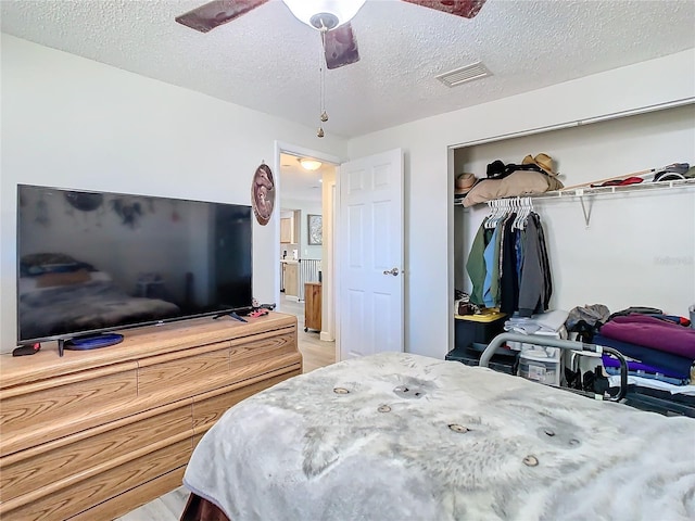 bedroom featuring ceiling fan, a closet, a textured ceiling, and light hardwood / wood-style flooring