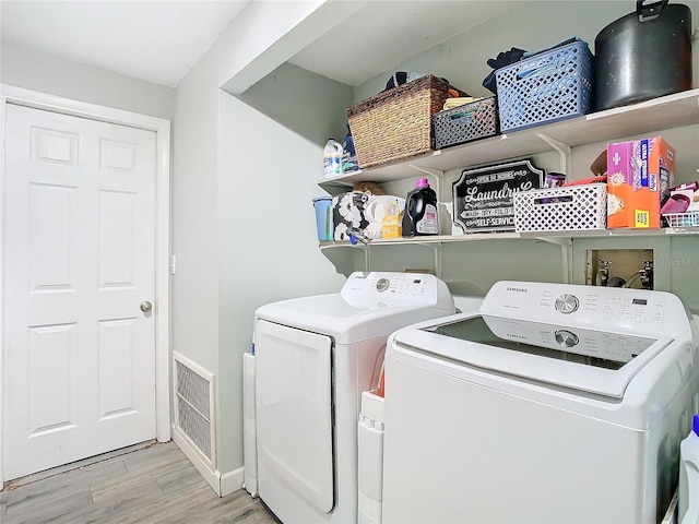 laundry room featuring light wood-type flooring and washer and clothes dryer