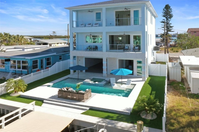 rear view of house featuring ceiling fan, an outdoor living space, a balcony, a patio area, and a swimming pool with hot tub