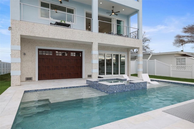 rear view of house featuring a balcony, ceiling fan, and a pool with hot tub