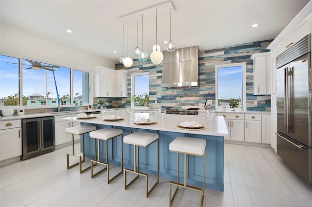 kitchen featuring white cabinets, stainless steel built in fridge, wine cooler, a kitchen island, and extractor fan