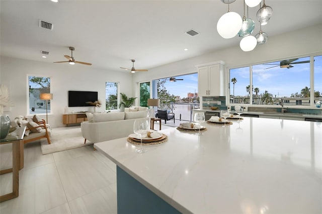 kitchen featuring white cabinetry, sink, tasteful backsplash, decorative light fixtures, and light tile patterned floors