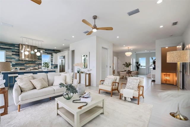 living room with ceiling fan with notable chandelier