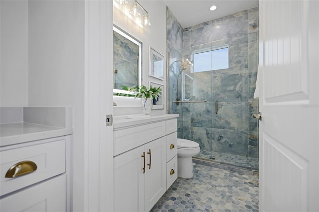 bathroom featuring vanity, a shower with shower door, and toilet