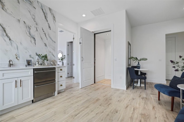 kitchen featuring white cabinets, light hardwood / wood-style floors, and sink