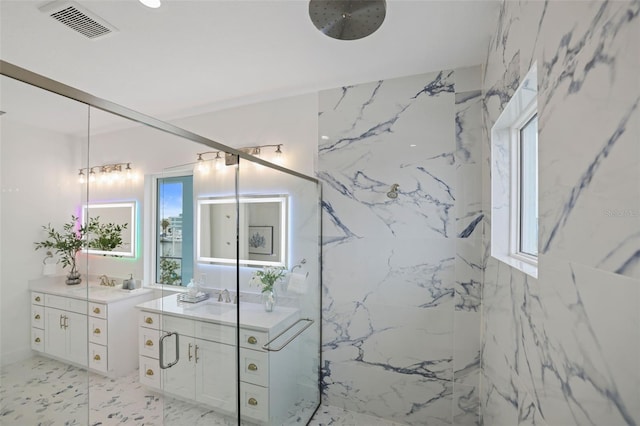 bathroom with tiled shower, vanity, and plenty of natural light