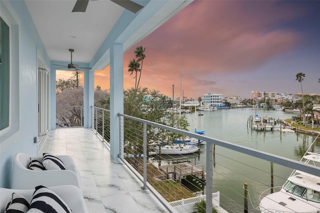 balcony at dusk featuring ceiling fan and a water view