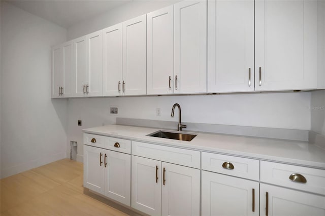 kitchen with white cabinetry, sink, and light hardwood / wood-style floors