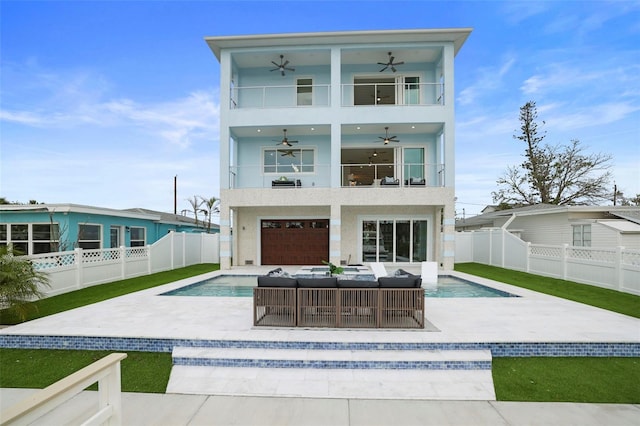 rear view of property featuring a balcony, outdoor lounge area, ceiling fan, a patio, and a fenced in pool