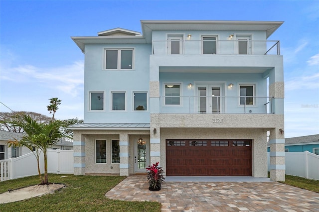 modern home featuring a balcony, a front yard, and a garage