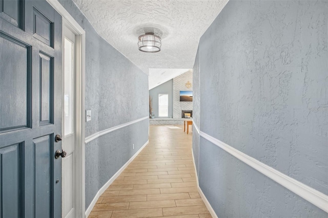 corridor featuring a textured ceiling, vaulted ceiling, and light hardwood / wood-style flooring