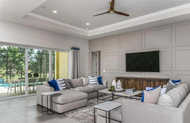 tiled living room featuring a tray ceiling, ceiling fan, and ornamental molding