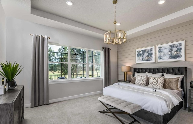 carpeted bedroom featuring an inviting chandelier and a tray ceiling