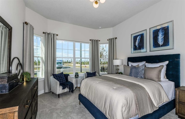 bedroom with light carpet, a textured ceiling, and multiple windows