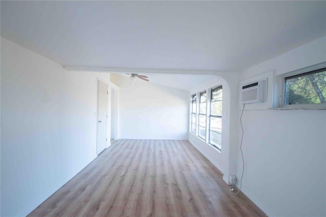 spare room with light hardwood / wood-style floors, a wall unit AC, and a wealth of natural light