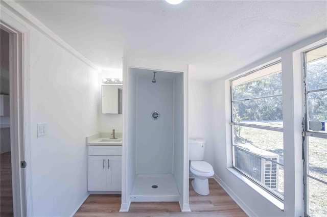 bathroom featuring walk in shower, wood-type flooring, a textured ceiling, toilet, and vanity