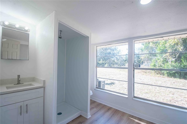 bathroom with hardwood / wood-style flooring, vanity, a healthy amount of sunlight, and a shower