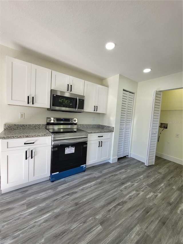 kitchen featuring light stone countertops, appliances with stainless steel finishes, a textured ceiling, dark wood-type flooring, and white cabinets