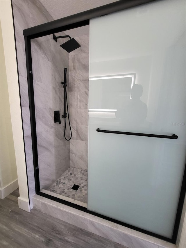 bathroom featuring a shower with shower door and hardwood / wood-style flooring