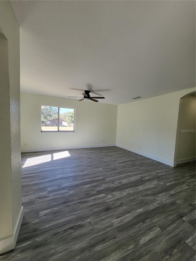 1302 E Annie St, Tampa, FL 33612 - empty room featuring ceiling fan, arched walkways, dark wood-type flooring, and a textured ceiling