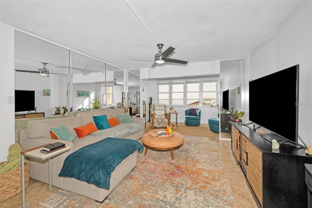 living room featuring ceiling fan, a textured ceiling, and light wood-type flooring