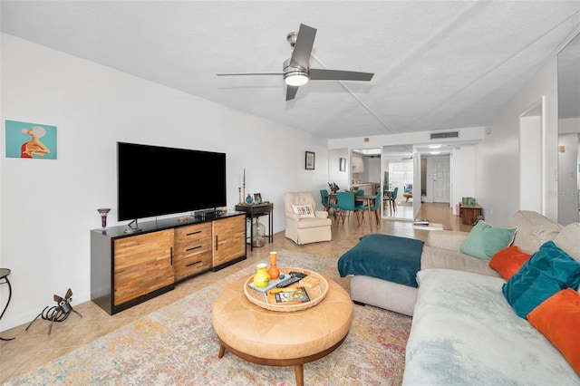 living room featuring ceiling fan, light tile patterned floors, and a textured ceiling