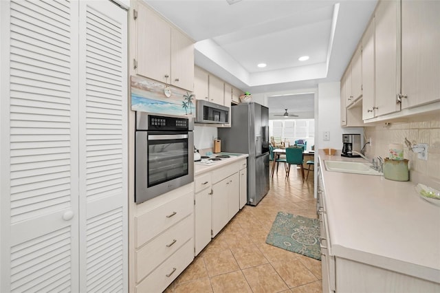 kitchen featuring appliances with stainless steel finishes, backsplash, ceiling fan, sink, and light tile patterned flooring