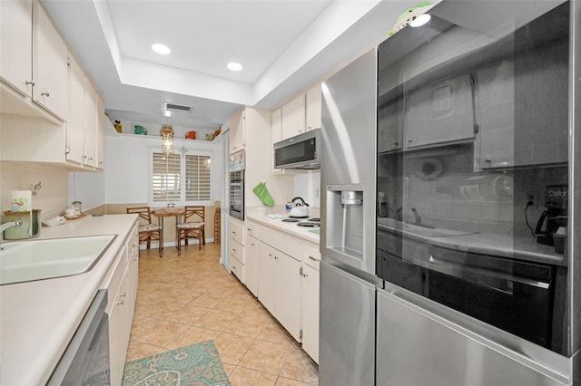 kitchen featuring appliances with stainless steel finishes, sink, decorative light fixtures, white cabinets, and light tile patterned flooring