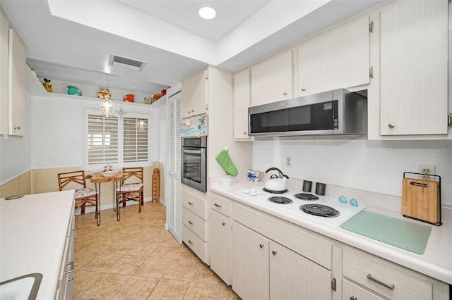 kitchen featuring white cabinetry, hanging light fixtures, light tile patterned floors, and stainless steel appliances