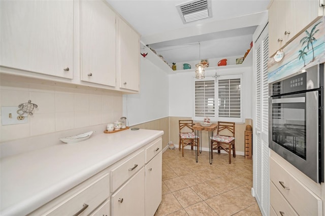 kitchen with white cabinets, stainless steel oven, and light tile patterned flooring