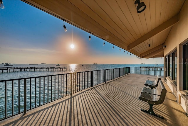 balcony at dusk featuring a water view