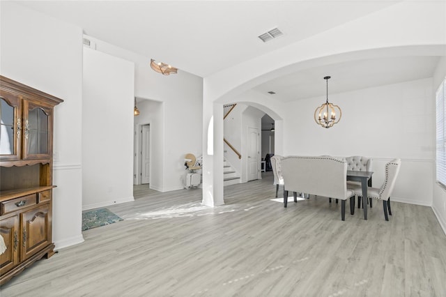 dining area with light wood-type flooring and an inviting chandelier