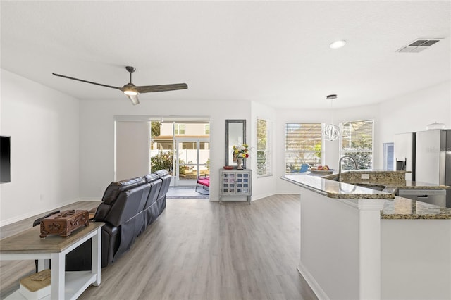 kitchen featuring decorative light fixtures, a healthy amount of sunlight, light wood-type flooring, and stone counters