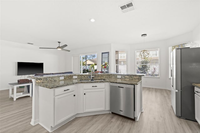 kitchen featuring white cabinetry, sink, an island with sink, light hardwood / wood-style floors, and appliances with stainless steel finishes