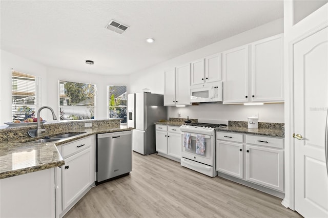 kitchen with dark stone countertops, white cabinetry, hanging light fixtures, and stainless steel appliances