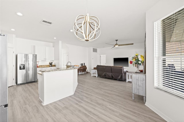 kitchen featuring stainless steel refrigerator with ice dispenser, light stone counters, decorative light fixtures, light hardwood / wood-style floors, and white cabinetry