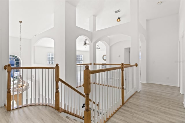 hall featuring a towering ceiling and light hardwood / wood-style flooring