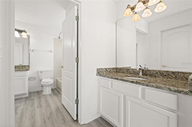 full bathroom with tub / shower combination, hardwood / wood-style floors, a chandelier, toilet, and vanity