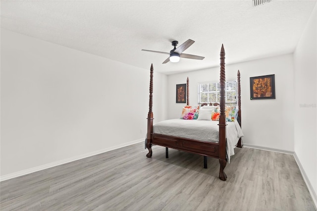 bedroom featuring ceiling fan, light wood-type flooring, and a textured ceiling