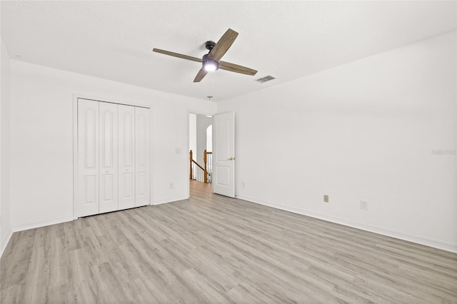 unfurnished bedroom with a textured ceiling, a closet, ceiling fan, and light hardwood / wood-style floors