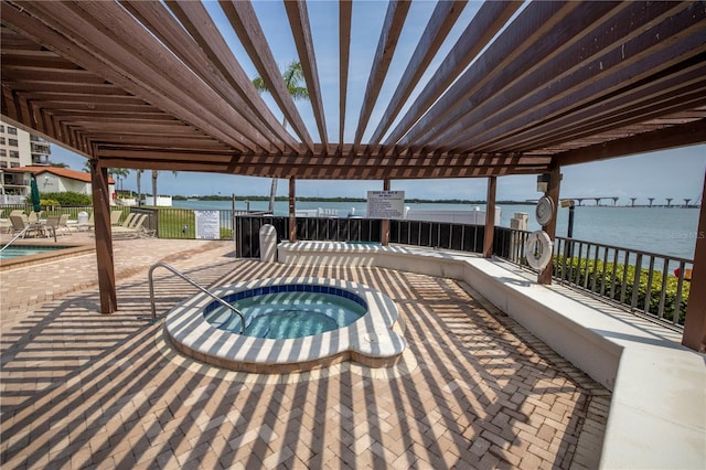 view of patio with a pergola, a swimming pool with hot tub, and a water view