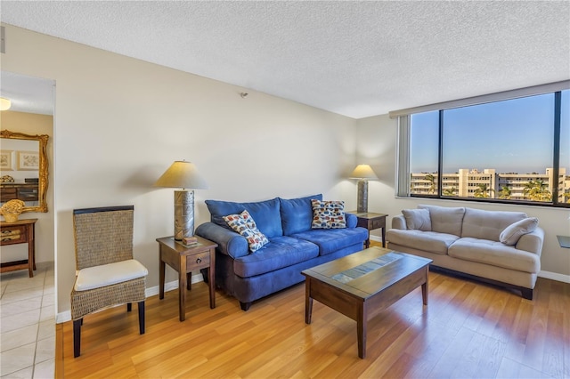 living room featuring expansive windows, light hardwood / wood-style floors, and a textured ceiling