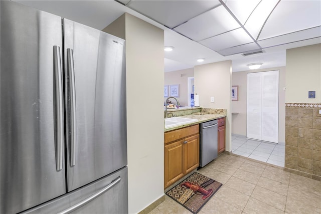 kitchen featuring light tile patterned flooring, sink, appliances with stainless steel finishes, and tile walls