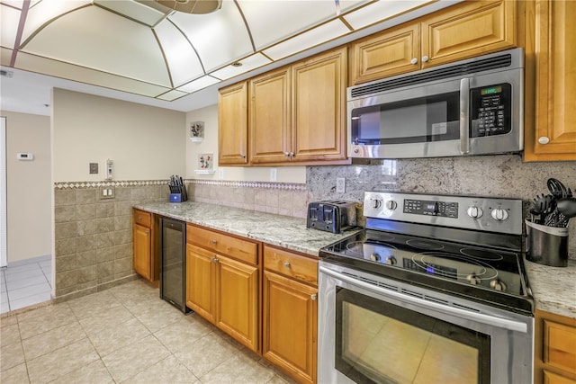 kitchen with light stone countertops, stainless steel appliances, beverage cooler, and light tile patterned flooring