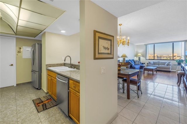 kitchen featuring appliances with stainless steel finishes, sink, pendant lighting, light hardwood / wood-style flooring, and a chandelier