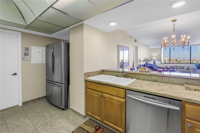 kitchen with sink, light stone counters, pendant lighting, a chandelier, and appliances with stainless steel finishes