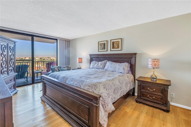 bedroom with a textured ceiling, access to outside, light hardwood / wood-style flooring, and floor to ceiling windows