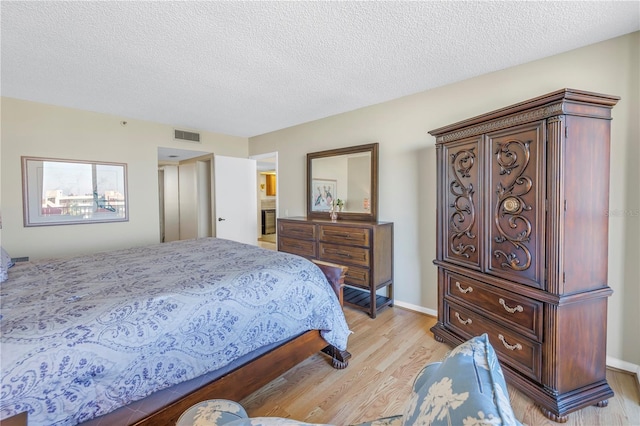 bedroom with light hardwood / wood-style floors and a textured ceiling