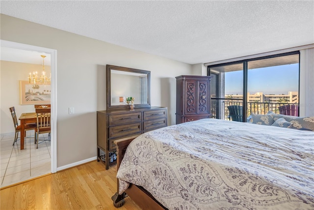 bedroom featuring a textured ceiling, light wood-type flooring, and access to outside